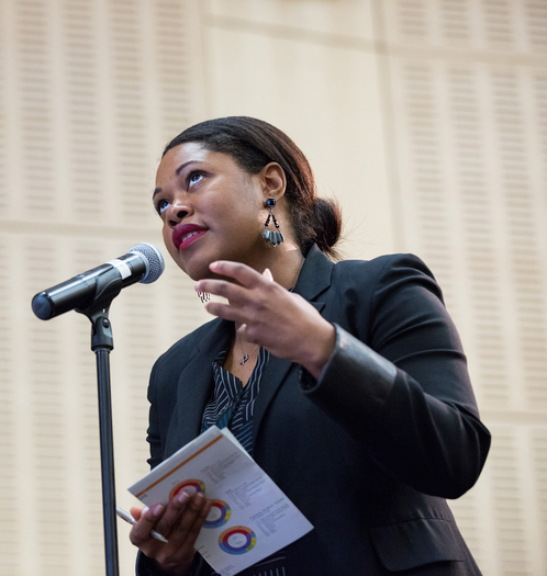 Dr. LaMisha Hill speaking at a microphone